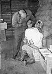 Dr. Roy Hemmerich performing a dental exam on a woman on board the R.M.S. Nascopie during a trip from Pond Inlet to Fort Ross. 29 August 1945.