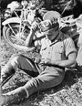 An unidentified Canadian despatch rider holding regimental shoulder flashes during the assault on the Gothic Line, Italy, ca. 26 August - 3 September 1944 [ca. August 26-September 3, 1944].