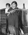 [Caroline Kaye (née Robert) carrying her son Selwyn in a beaded baby belt, Teet'lit Zheh (also known as Fort McPherson), Northwest Territories]. Original title: Dene woman [Caroline Kaye (nee Robert)] Dene woman [Caroline Kaye (nee Robert) with her son Selwyn, ] carrying baby in a beaded baby belt 1947.