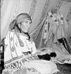 Mrs. Eagle Tail, wife of Sarcee head chief, in traditional dress, at Teepee Village, Victoria Park, during the Calgary Stampede July 1945