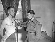 An unidentified parachute candidate undergoing a medical examination at A35 Canadian Parachute Training Centre, Camp Shilo, Manitoba, Canada, 20 March 1945 March 20, 1945