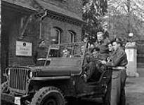 Private Maurice Richard (right), Canadian Provost Corps, talking with students of the Khaki University of Canada, who ride in a jeep driven by Lance-Bombardier R.S. Hughes, Leavesden, England, 15 April 1946 April 15, 1946