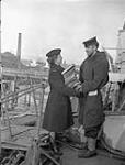 Leading Wren Ruth Church, Women's Royal Canadian Naval Service (W.R.C.N.S.) delivering a supply of library books to Able Seaman Bill Swetman of H.M.C.S. PETROLIA, Londonderry, Northern Ireland, November 1944 November 1944.