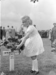 A Dutch girl placing flowers on the grave of Rifleman C.H. Baxter, Royal Winnipeg Rifles, who was killed in action on 12 October 1944, Netherlands, June 1946 June, 1946.