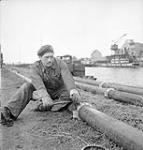 Sapper J.D. Martel, 3rd Battalion, Royal Canadian Engineers (R.C.E.), tightening couplers during construction of the Ostend-Ghent oil pipeline, Ostend, Belgium, 18 October 1944 October 18, 1944.