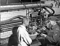 Dr. Paul Larose (right) of the National Research Council of Canada talking with a German scientist in the chemical laboratory of a metal alloy plant, Heddesheim, Germany, ca. 4 - 10 September 1945 [ca. September 4 - 10, 1945].