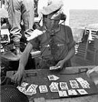 Private F.J. Tagobald of a Canadian Highland regiment playing solitaire while on Bofors gun duty aboard the troopship H.M.T. NEA HELLAS en route to Philippeville, Algeria, 5 July 1943 July 5, 1943.