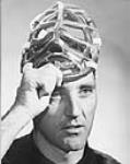 Jacques Plante soulevant son masque de joueur de hockey 1960