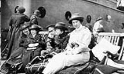 Nursing sisters sitting on deck of ship with a soldier vers 1916.