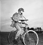 Private Tom J. Phelan, 1st Canadian Parachute Battalion, who was wounded on 16 June 1944 at Le Mesnil, rides his airborne folding bicycle at the battalion's reinforcement camp, England, 1944 1944.