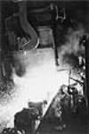 Molten steel being poured from a giant ladle into 17 ton capacity into molds, Steel & Co. of Canada / De l'acier fondu s'écoule d'une poche de coulée géante dans une lingotière d'une capacité de 17 tonnes, Steel Co. of Canada, Hamilton Apr. 1963
