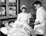 Dr. Osborne performs a spinal puncture operation on Eskimo girl at Pangnirtung Hospital. [Nuvvika (patient), Arnalukakutaak (nurse) and Luutaakutaak (doctor)] 1947