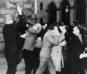 Unidentified official beating back a group of people, some of whom are shielding their faces, during an apparent demonstration during the Depression ca. 1929 - 1936