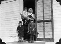 Mrs. Paul Horvath with her children at the farm house where she is employed, Marchand, Manitoba 1930