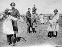 Jewish children dancing to the music of the mouth organ on the grounds of the Tiferes Israël School. Lipton, Saskatchewan 1916