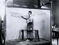 Artist painting a diorama of the Gaspé area for the new Victoria Memorial Museum in Ottawa Apr. 1913