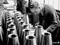 Male munitions worker measuring shells as part of testing process déc. 1939