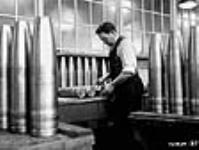 Male munitions worker measuring shells as part of testing process déc. 1939