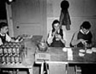 Des ouvriers scellent l'intérieur d'un masque à gaz dans la salle d'assemblage de l'édifice de l'annexe de recherche 17 oct. 1940