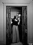 Une jeune fille de la haute société de Montréal et son cavalier se préparent à partir pour le bal « Aide à la Grande-Bretagne », qui se donne à l'hôtel Ritz Carleton, mars 1941 Mar. 1941