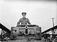 Brigadier Kenneth Stuart, D.S.O.,M.C., stands in the first Canadian-built tank, the Valentine Tank, at the Angus Shops of the Canadian Pacific Railway 27 mai 1941