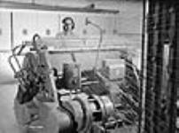 Une travailleuse utilise un ourdissoir à l'usine de la Montreal Cottons Ltd vers mars 1942