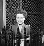 Une travailleuse pose avec des fusils Enfield terminés à l'usine de la Small Arms Ltd. à Long Branch 26 May 1942