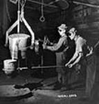Workmen wearing protective goggles pour molten alloy steel from its carrying bucket into a pouring ladle in the foundry of the Ford Motor Company of Canada 2 jui1. 1942