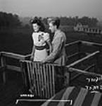 Boyfriend of female Dominion Arsenals Ltd. munitions plant worker opens a gate for her while on a date 24 août 1942