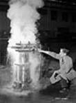 Un ouvrier ajuste le débit d'eau lors du refroidissement d'un manchon de culasse d'un canon naval de 4 pouces à l'usine National Railways Munitions Ltd 9 Feb. 1943