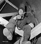 Ovilla Koriac, a welder for the Shipshaw Power Development project, perches on a ceiling beam on the inner wall of the penstock Jan. 1943