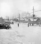 Le long de la route principale du campement de Shipshaw, des hommes reviennent du travail à midi. Aménagement hydroélectrique de Shipshaw (Québec) janv. 1943