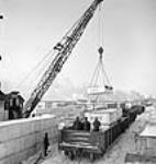 Cranes load shipping crates of Chevrolet vehicles into railway cars févr. 1943