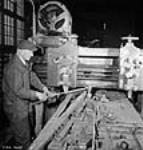 Un ouvrier au dépôt de récupération démonte et récupère des pièces métalliques appelées « grenouilles » Feb. 1943