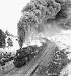 Heavy freight engine, towing a mile-long line of supplies, moves out of the railway yards Jan. 1943