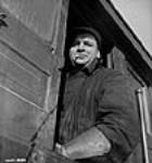 Male engineer and Dinkie Skinner Jean-Baptiste Normand stands in the doorway of a dinkie on a railway track at the Arvida plant of the Aluminum Company of Canada janv. 1943