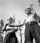 Lumberman Ollie Brackoos accepts a chew of tobacco from his partner Jack Crosse Apr. 1943