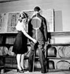 Une ouvrière, à l'usine Standard Overalls Company, mesure le dos d'un modèle masculin essayant l'uniforme des camps d'internement Mar. 1943