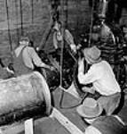 Des ouvriers installent un clapet de retenue de 24 pouces sur une prise d'eau à l'usine de la Société Polymer Limitée June 1943