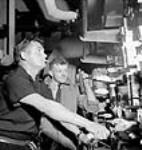 Edwin Pascoe, third engineer, checks the switchboard while Norman Thompson, Sunderland, member of the new crew looks on, aboard a new cargo ship during its test run July 1943