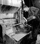 Workman scoops a small sample of wood pulp emerging from the grinder at the International Pulp and Paper Company mill Sept. 1943