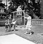 Mrs. Jack Wright waves goodbye to her two sons Ralph and David left at a day nursery with a nursery worker while Mrs. Wright goes to work at a munitions factory sept. 1943