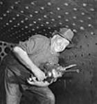 Un poseur de rivets fait des trous à rivets dans la chaudière d'une locomotive X/Dominion pour expédition en Inde Nov. 1943