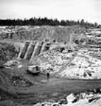 Vue du bouchon de roche et de l'excavation retenant les eaux entre le lacMarmion et le lac Raft pendant la construction d'une mine à ciel ouvert 26 Jan. 1944