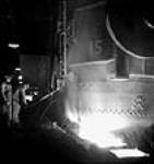 Workmen operate ladle to pour molten steel into ingot moulds at the Stelco Steel Company of Canada plant mars 1944