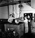 Workmen lower a torpedo into a water bath for a pressure test at the John Inglis Co. plant mai 1944
