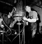 À l'usine John Inglis Co., les ouvriers William Butcher et Lloyd Cowison effectuent un cordon de soudure sur une tête de torpille après que la couronne ait été frettée à chaud sur cette dernière May 1944