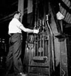 Workman William Bruder conducts an operation known as vertical lap rifling grooves in the John Inglis Co. plant in Toronto where .303 Vickers machine gun barrels are turned out mai 1944