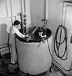 Un employé s'occupe d'un réservoir de refroidissement utilisé pendant la fabrication de pénicilline aux laboratoires Connaught May 1944