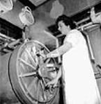 Une employée ouvre un autoclave utilisé pour stériliser des flacons qui servent à produire de la moisissure de pénicilline aux laboratoires Connaught mai 1944